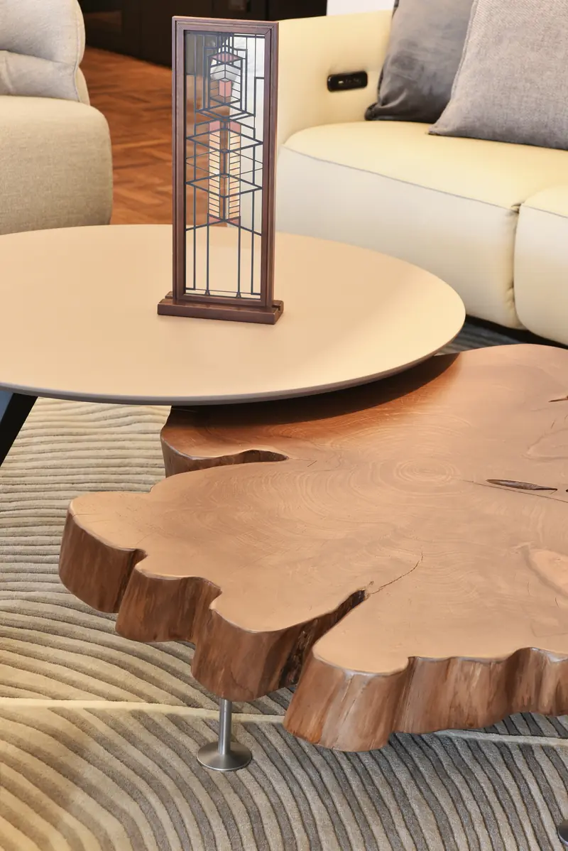 Mesa baja hecha con una rodaja de tronco bajo una mesa redonda clara, junto al sofá