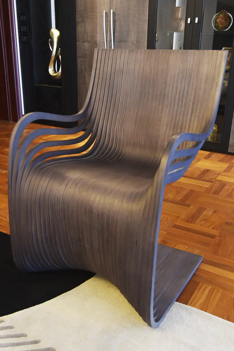 Silla de láminas de madera curvada sobre el parqué y una alfombra clara