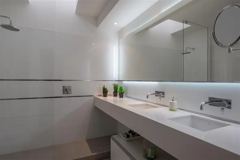 Baño blanco con mesada volada, doble bacha y espejo con luz