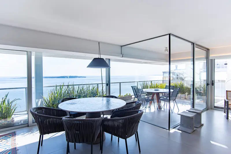 Comedor redondo dentro del jardín de invierno de cristal, abierto a la terraza y al horizonte