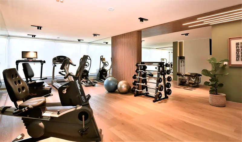 Gimnasio con bicicletas, máquinas y pesas sobre suelo de madera