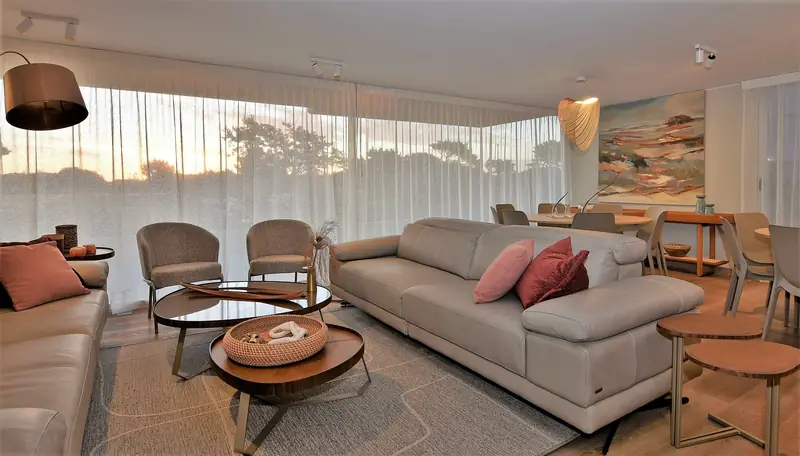 Salón de planta baja con sofás claros, cojines rosados y lámpara de pie de cobre