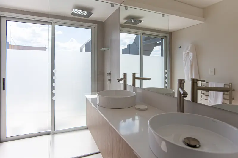 Baño con lavabo de apoyo blanco sobre la encimera y puertas correderas de vidrio esmerilado